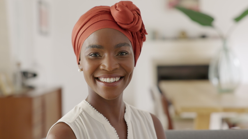 Portrait of smiling middle aged woman with headscarf at home. Cheerful mid adult black woman with turban looking at camera. Happy mid mature lady wearing traditional african scarf on head. Royalty-Free Stock Footage #1083153853
