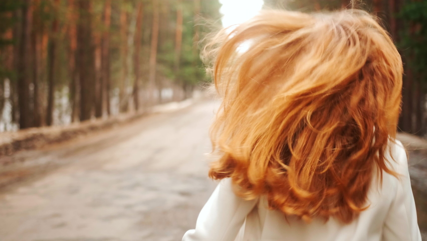 Beautiful woman with a magnificent golden hair. Fun happy young girl shake her head to make hair flying. Attractive young lady turns around and looks into the camera