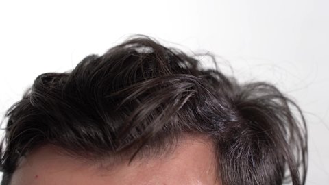 Close-up of Hair on a Man's Head. Runs Hand Through Hair on White Background. Personal Hygiene Concept
