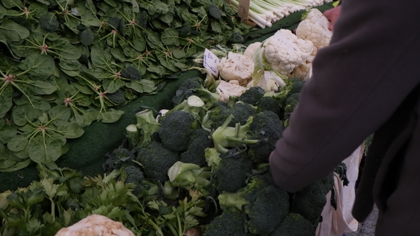 Broccoli, spinach and cauliflower are sold on the counter at the public market. These vegetables, which are also vegetarian, are very healthy. The woman buys broccoli from these vegetables. | Shutterstock HD Video #1083173122