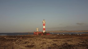 A young man flying a drone at the Toston lighthouse at sunset, Punta Ballena, near the town of El Cotillo, Fuerteventura Island, Canary Islands. Spain, 4k video	