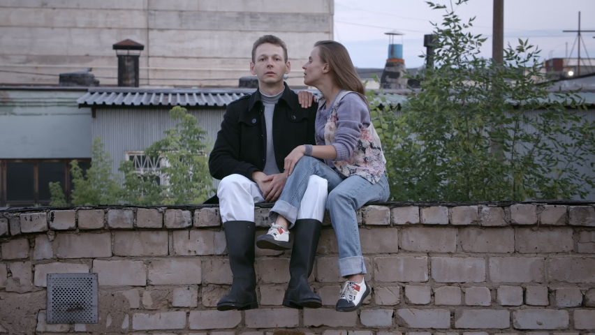 Video of young couple sitting on the brick roof in summer