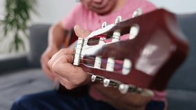 man in raspberry shirt plays guitar, close-up of male hands, teaches students online skills, records training video, concept Home Recording Studio, selective focus at shallow depth of field