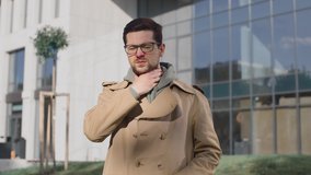 Close up portrait of unwell caucasian man standing at the street and covering mouth with hand while coughing and feeling sore throat. Virus infection concept - Powered by Shutterstock - Get 15% off with code: PIKWIZARD15