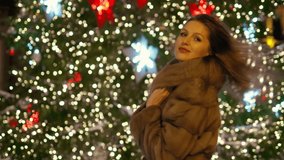 Beautiful woman smiling at you near christmas tree in city center