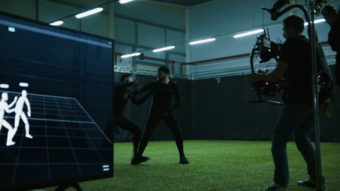 Cameraman filming actors performing some fight moves wearing motion capture suits as a game characters. Motion capture is an unparalleled method for making animated characters move more realistically
