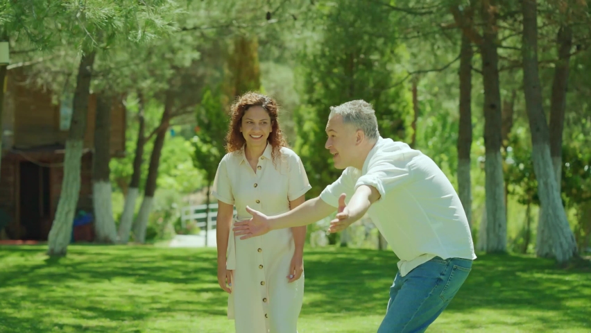 Cute little girl running with open arms on green grass. The father welcomes his daughter with open arms and throws her into the air. Happy family portrait.