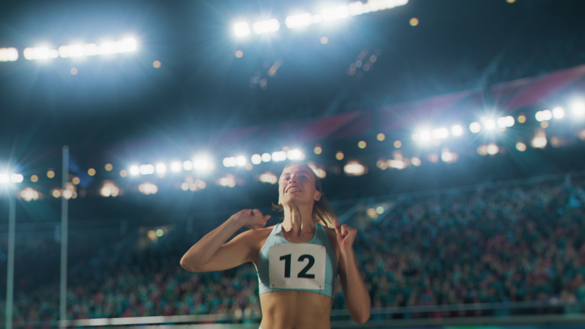 Portrait of Professional Female Athlete Happily Celebrating New Record on a Sport Championship with Stadium Crowd Cheering. Young Sportswoman Raising Arms Cheering. Winning, Victory, Success Royalty-Free Stock Footage #1083195010