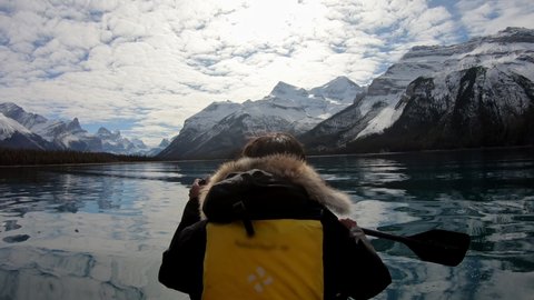 Man traveler rowing a canoe into the Spirit Island with Canadian Rockies on Maligne lake at Jasper national park, Canada