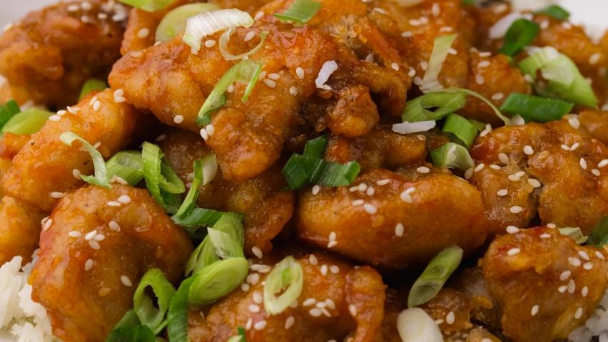 Asian style crispy sweet sesame chicken with rice and spring onion. Rotating video | Shutterstock HD Video #1083197368