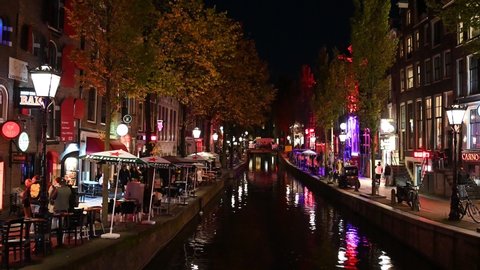 Amsterdam, Netherlands, October 2021: Famous red light District at night. Borthels and sex shops. Prostitutes work here. Streets full of tourists and visitors. Holland.