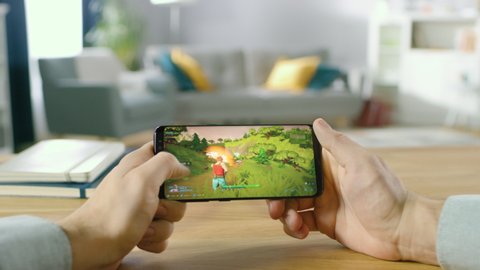 First Person POV: Person Playing Video Game on Smartphone in Landscape Mode. Professional Gamer Playing in Real 3D Shooter at Home. True Gameplay Showing Arcade Online Multiplayer