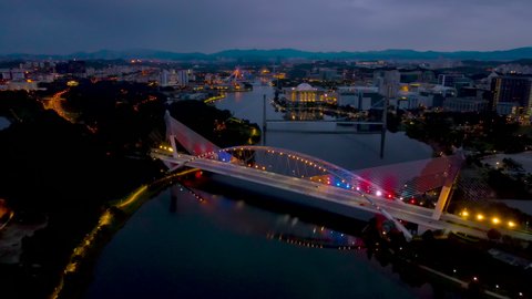 PUTRAJAYA, MALAYSIA - DECEMBER 1ST, 2021 : Aerial shots of Putrajaya Saujana bridge during dusk with malaysian flag lights up