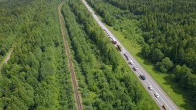 A huge highway with cars. Clip. The track is on the background of a green summer forest with huge trees on a summer day.
