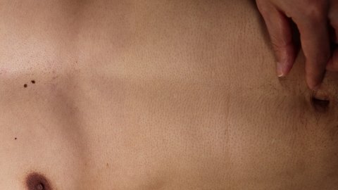 Naked Japanese man touching unwanted hair around the navel