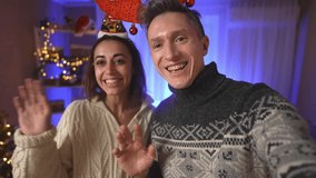 POV first person view happy cheerful excited couple, woman in festive Elf Cap and man in red reindeer antlers headband taking selfie on background of decorated house with christmas tree - Powered by Shutterstock - Get 15% off with code: PIKWIZARD15