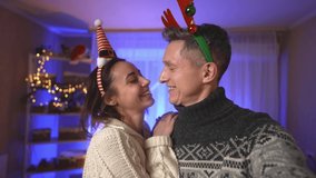 POV first person view lovely couple wearing in festive Christmas headbands making video selfie and talking at home with lights background