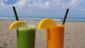 Green and orange refreshing tropical drinks in glasses on the sandy beach with ocean waves and sky in the background - Powered by Shutterstock - Get 15% off with code: PIKWIZARD15