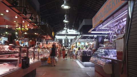 Barcelona , Spain - 08 01 2021: Barcelona - Mercado de La Boqueria, long steady tracking shot through closed market with stalls and shoppers, Covid-19 Pandemic