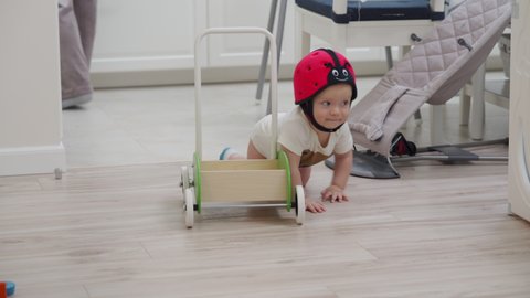 Baby wearing safety helmet crawling on the floor, 8 month old caucasian toddler exploring all around the house. High quality 4k footage