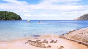 Nai harn beach Phuket,Thailand.Beautiful sea middle two mountains blue sky background.Landscape view beach sea and sand on summer. Sailing on ocean during sunset.  Video 4K