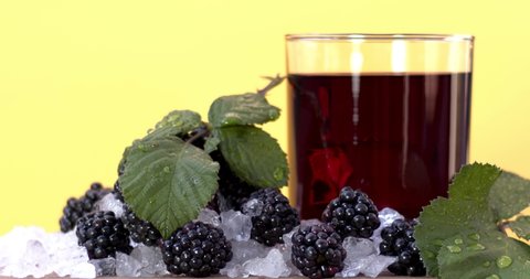 Blackberry juice is poured into a crystal transparent glass on ice with red, natural blackberries on a white background, vitamin and delicious sweet juice. Fimled on cinema camera, 8K downscale. 4K.