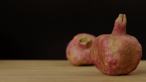 Red pomegranate on a wooden board on a black background, natural and vitamin red fruits. Slow motion, filmed on high speed cinema camera, 8K downscale, 4K.