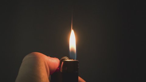 Male hand with a gas lighter. The man makes fire. super slow motion footage. gas lighter video.black background.