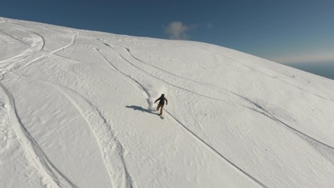 Aerial view athlete freeride snowboard rider on fresh snow slope mountain sports FPV drone Abkhazia. Active male enjoy extreme leisure activity with Black Sea overview winter nature landscape