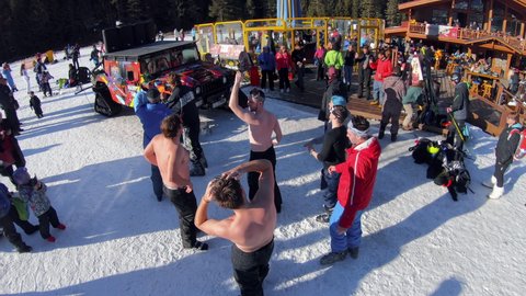 Bansko, Bulgaria - 14 Jan, 2021: Group of skier friends snowboarders having fun on the top of mountain dancing in slow motion