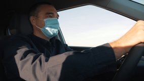 A man driver sits in a car with a protective mask during the coronavirus pandemic. A businessman in a medical mask is driving a car. Traveling by car during a pandemic with protective equipment - Powered by Shutterstock - Get 15% off with code: PIKWIZARD15