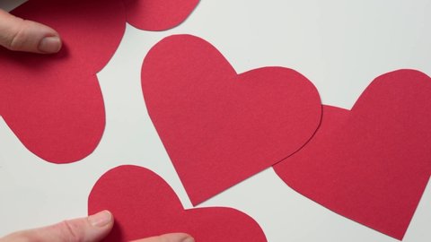 hands moving many red hearts shape made from cut paper on white background. Valentine's Day love concept. Mother's Day celebration holidays. DIY preparation present gift decorations. 
