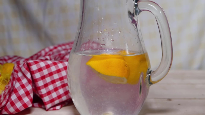 Fresh sliced lemons in pitcher of water medium static shot selective focus slow motion