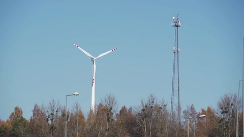 Looped. Wind turbine on a hill among the trees. Transmitting tower for cellular telephony.
