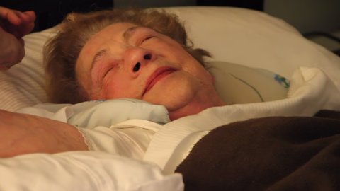 Elderly woman in bed wakes up and yawns