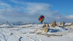 AERIAL. Top view to the colourful hot air balloon flying above winter landscape. 