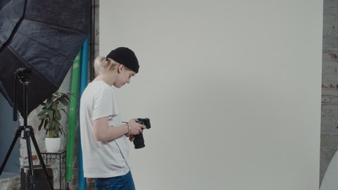 Young Photographer Standing in Her Modern Photo Studio Waiting for The Model. Beautiful Caucasian Influencer Model Coming In Shaking Photographers Hand and Starts Posing In Front of the Camera.