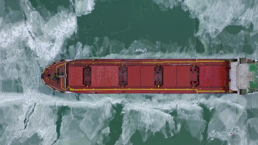 Aerial above epic huge steel icebreaker breaks ice by bow of ship and floats in large sea ice floes. Maintaining navigation in a frozen sea channel laying. Self-propelled specialized vessel red ship Royalty-Free Stock Footage #1083235738