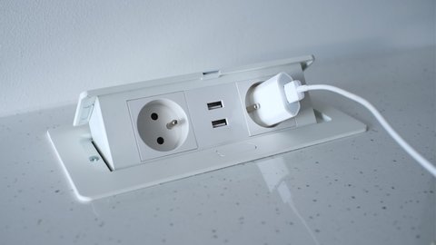 Caucasian Male Disconnecting Phone Charger from Retractable Pop Up Power Outlet Installed on Kitchen Counter