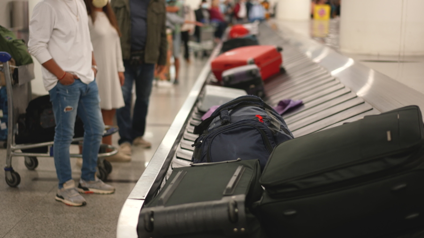 Passenger people at airport or railway station waiting arrival of their luggage. Suitcases and bags carried by convey belt or carousel. Tourists, travelers at terminal runway lobby before flight. Royalty-Free Stock Footage #1083255121