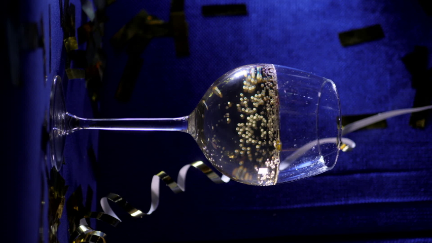 glass of champagne sits on velvet blue sofa vertical