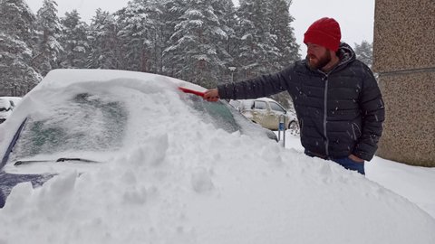 Man Shoveling Snow off Car.
Winter time, clearing snow from a car windshield.