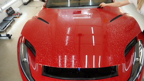 Close up to PPF installation process on a front headlight and hood. PPF is a Paint Protection Film which protect paint from scratches and stone chips. Concept of: Guard, Protect, Car, New, Work.	
