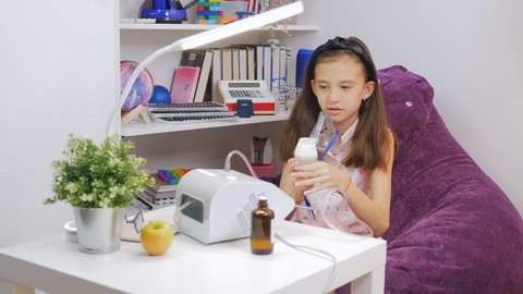 Portrait of cute child is sick bronchitis or asthma and breathe through inhaler at home Little girl makes inhalation with medical nebulizer while sitting at the table.