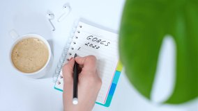 Female hand writes goals 2022 in notebook on white background top view. - Powered by Shutterstock - Get 15% off with code: PIKWIZARD15