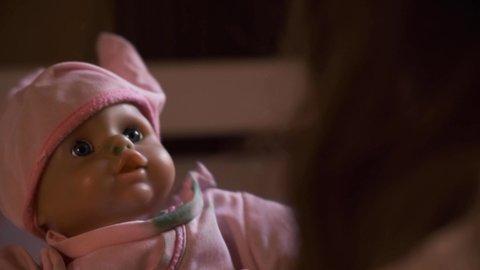 Kid playing with doll. Scary doll with pink hat and scary eyes. baby doll help by a child. horror movie