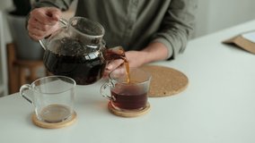 woman in a linen shirt pours tea into two transparent cups. hospitality concept, hostess treats guest to tea - Powered by Shutterstock - Get 15% off with code: PIKWIZARD15