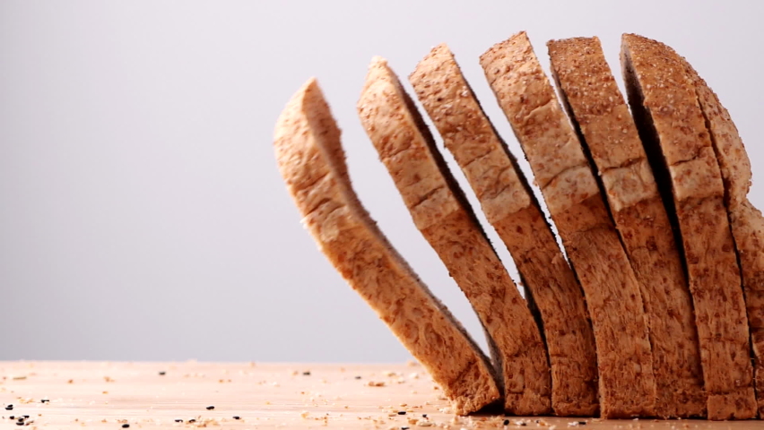 Close up whole wheat multigrain bread sliced falling on wooden table on white background, slow motion. Loaf of Bread, Slice of food, Healthy Food Concept. | Shutterstock HD Video #1083270916