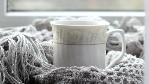 Cozy home with cup of coffee and a book. Hygge style. Mug of black coffee wrapped in warm scarf on wooden board. Top view, vintage style, Still life.