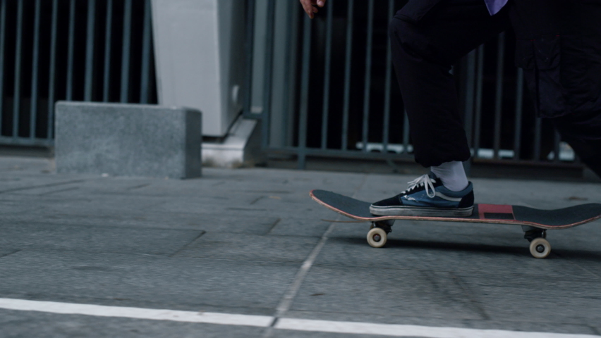 Unknown active man feet riding on skateboard outdoor. Unrecognizable sporty hipster making trick with skateboard on urban background in slow motion. Unknown skater guy jumping kickflip outside. | Shutterstock HD Video #1083276850